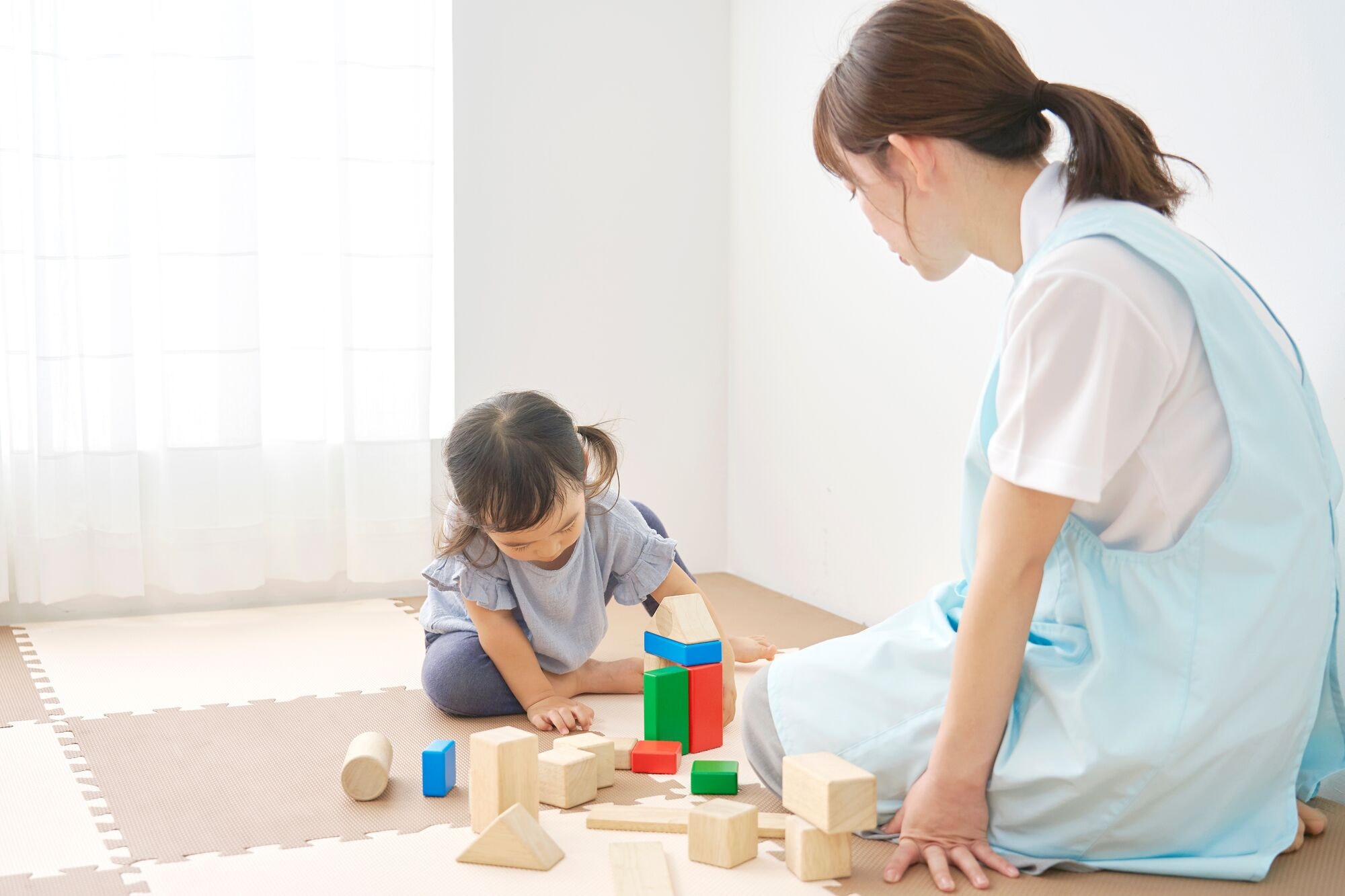 積み木で遊ぶ園児を見守る保育士